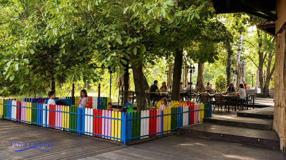 Ograđeno dečije igralište na terasi, deca se igraju nadomak stolova