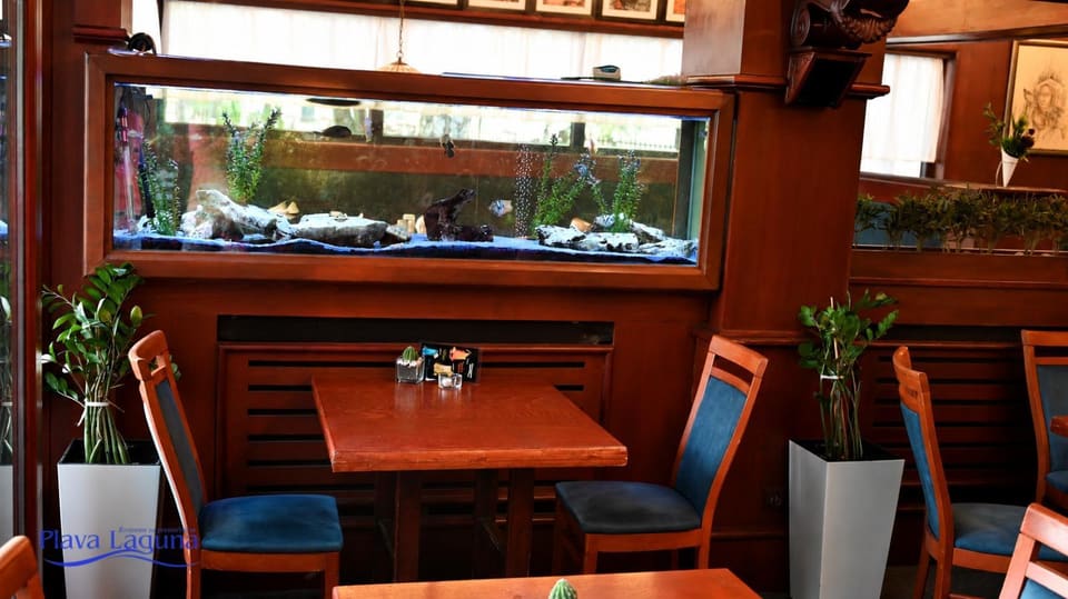 Veliki zidni akvarijum u sali restorana, sto za dvoje ispred njega